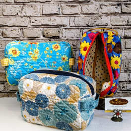 Three floral-patterned quilted zip pouches on a table