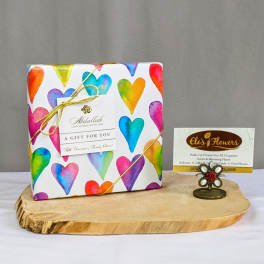 Heart-patterned chocolate gift box on a wooden board with a small flower-shaped card holder.