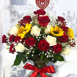 Bouquet of red and white roses with yellow sunflowers in a glass vase
