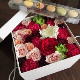 Box of mixed roses and carnations with macarons on top