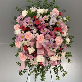 Pink and white floral wreath on a stand with a satin ribbon