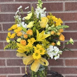 Yellow and white mixed bouquet in a glass vase with a yellow ribbon