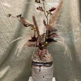 Tall dried floral arrangement in a ceramic vase with feathery plumes and gold accents