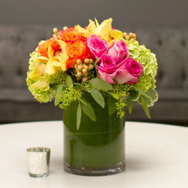 Colorful bouquet of roses and hydrangeas in a green glass vase