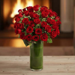 Tall glass vase filled with a large, dense bouquet of red roses
