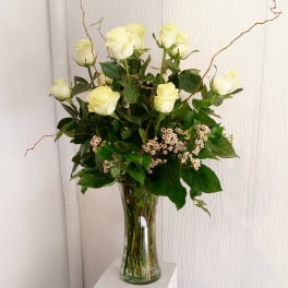 White roses in a clear glass vase with small white filler flowers