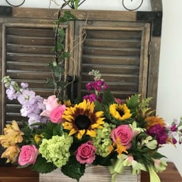 Mixed bouquet with sunflowers, pink roses, and hydrangeas in a wooden box