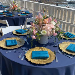Beachside table setting with a pastel floral centerpiece in a white vase