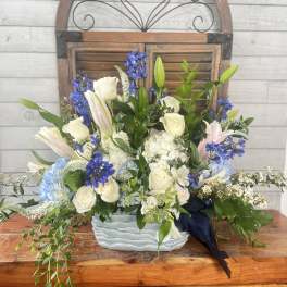 Blue and white floral arrangement in a ceramic vase with trailing greenery