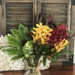 Mixed bouquet of yellow and burgundy orchids in a glass vase