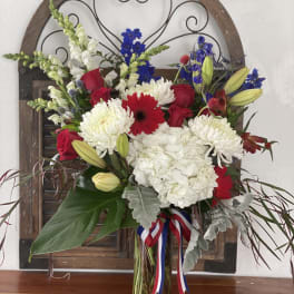 Mixed bouquet of red roses, white chrysanthemums, and blue flowers in a glass vase