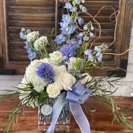 Blue and white floral arrangement in a glass vase with a ribbon