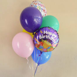 Cluster of colorful birthday balloons against a plain wall