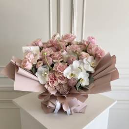 Pink and white bouquet with roses and orchids wrapped in blush paper