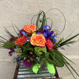 Colorful bouquet with orange roses, purple irises, and a green ribbon in a vase