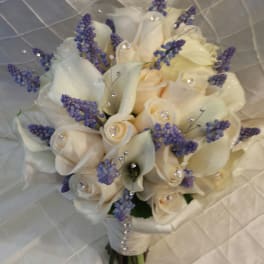 Cream roses and purple filler flowers in a bridal bouquet