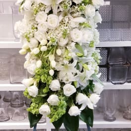 Tall white floral standing spray with lilies and roses on an easel