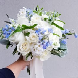 White rose bouquet with pale blue flowers and ribbon wrap