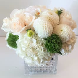 White and blush bouquet in a clear square vase