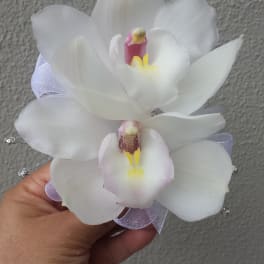 Handheld corsage with two white orchid blooms and a pale ribbon