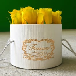 Yellow roses in a white round gift box with gold lettering