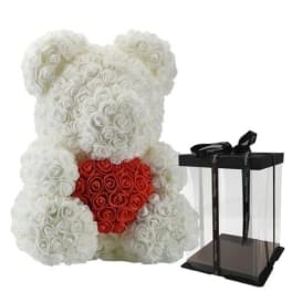 White rose teddy bear with a red rose heart beside a clear gift box