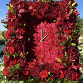 Large red floral clock covered in roses and lilies