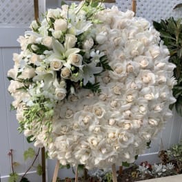 Large white floral wreath on an easel with roses and lilies