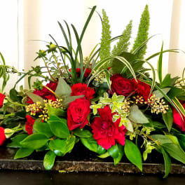 Red roses and carnations arranged on a low rectangular base