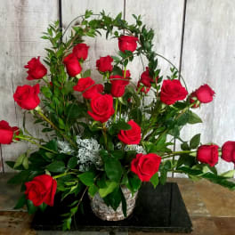 Red roses arranged in a basket with arched greenery