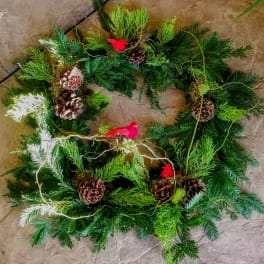 Circular evergreen wreath with pinecones and small red bird ornaments