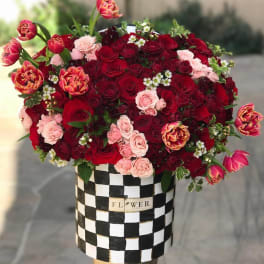 Bouquet of red and pink roses in a black-and-white checkered box