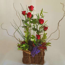 Tall arrangement of red roses in a rustic bark-covered container