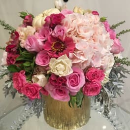 Pink and cream floral arrangement in a gold vase