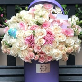 Bouquet of pink and white roses in a purple hatbox with a ribbon