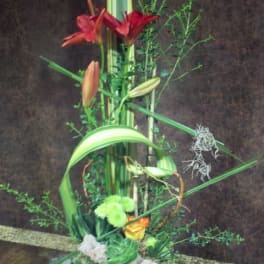 Tall floral arrangement with red lilies and succulents in a gray vase
