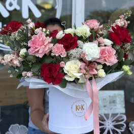 Large bouquet of red, pink, and white roses in a white hatbox with a pink ribbon.