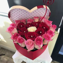 Heart-shaped box of pink and red roses with a decorative heart topper