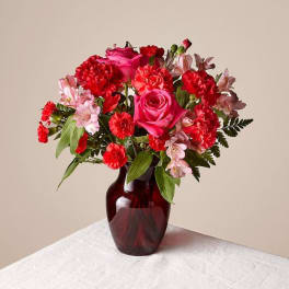 Pink and red flower bouquet in a dark glass vase