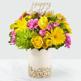 Bright mixed bouquet in a white vase with a glittery "Happy Birthday" topper