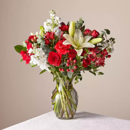 Red and white mixed flower bouquet in a clear glass vase
