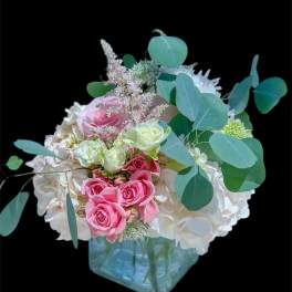 Pink and white roses in a blue glass vase with eucalyptus