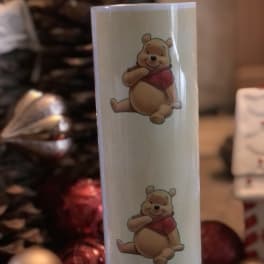 White candle with two Winnie the Pooh illustrations