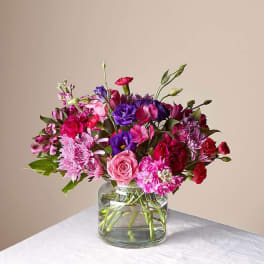 Mixed pink and purple flowers arranged in a clear glass vase
