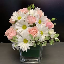 Pink roses and white daisies arranged in a clear glass vase