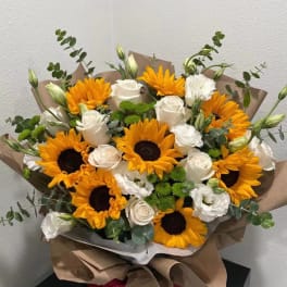 Bouquet of sunflowers and white roses wrapped in brown paper