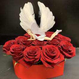 Red roses in a red box with a small fairy figurine and white wings