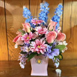 Pink and blue artificial flower arrangement in a pink vase