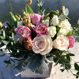 Low arrangement of blush roses and pink tulips in a whitewashed wooden box