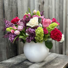Mixed pink, white, and purple flowers in a white vase